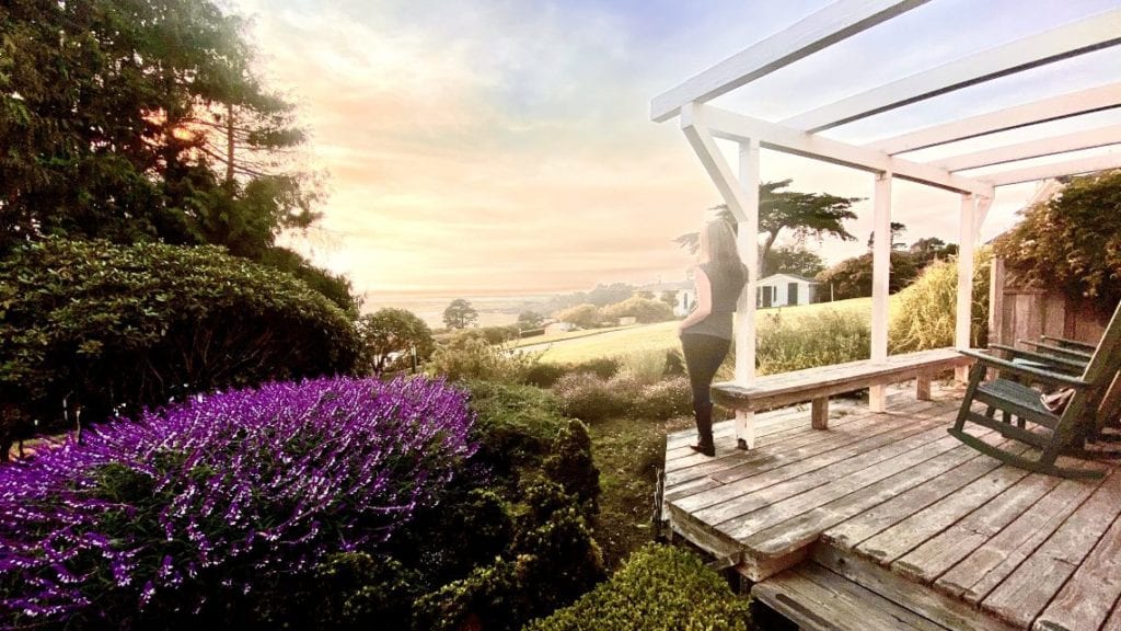 Photo of a woman standing on a deck looking at the ocean